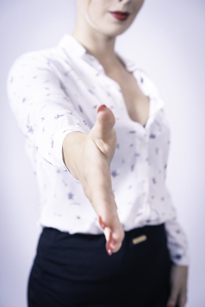 Close-up of a woman in a professional attire reaching out for a handshake symbolizing business opportunities.